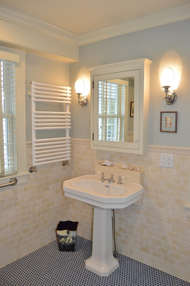 Bild på ett vintage badrum, med mosaikgolv, luckor med profilerade fronter, vita skåp, en kantlös dusch, en toalettstol med hel cisternkåpa, beige kakel, keramikplattor, blå väggar och ett piedestal handfat