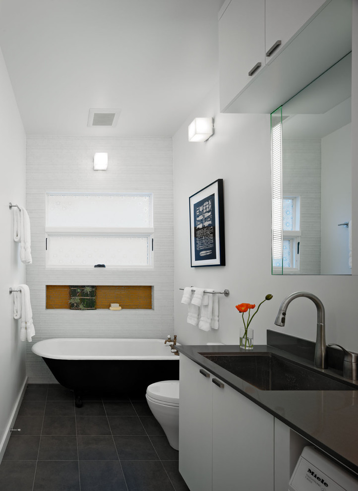 This is an example of a medium sized contemporary half tiled bathroom in San Francisco with mosaic tiles, a submerged sink, a one-piece toilet, flat-panel cabinets, white cabinets, engineered stone worktops, white tiles, white walls, porcelain flooring and a laundry area.