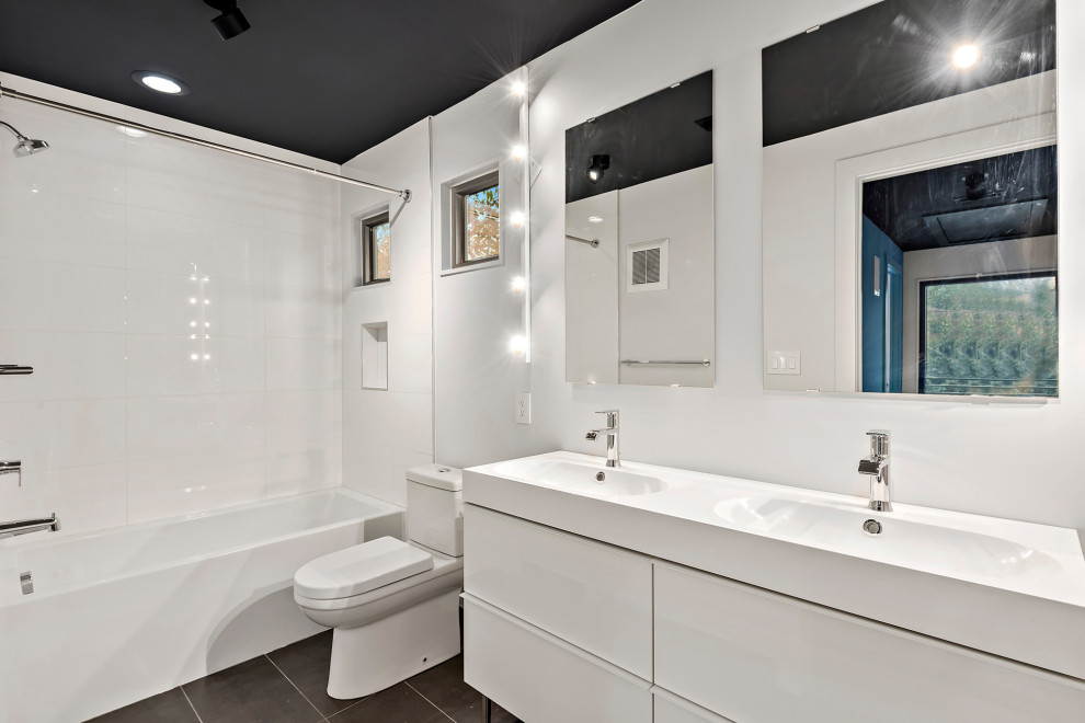 Inspiration for a mid-sized modern kids' white tile and porcelain tile porcelain tile and black floor bathroom remodel in Charlotte with flat-panel cabinets, white cabinets, a two-piece toilet, white walls, an integrated sink, quartz countertops and white countertops