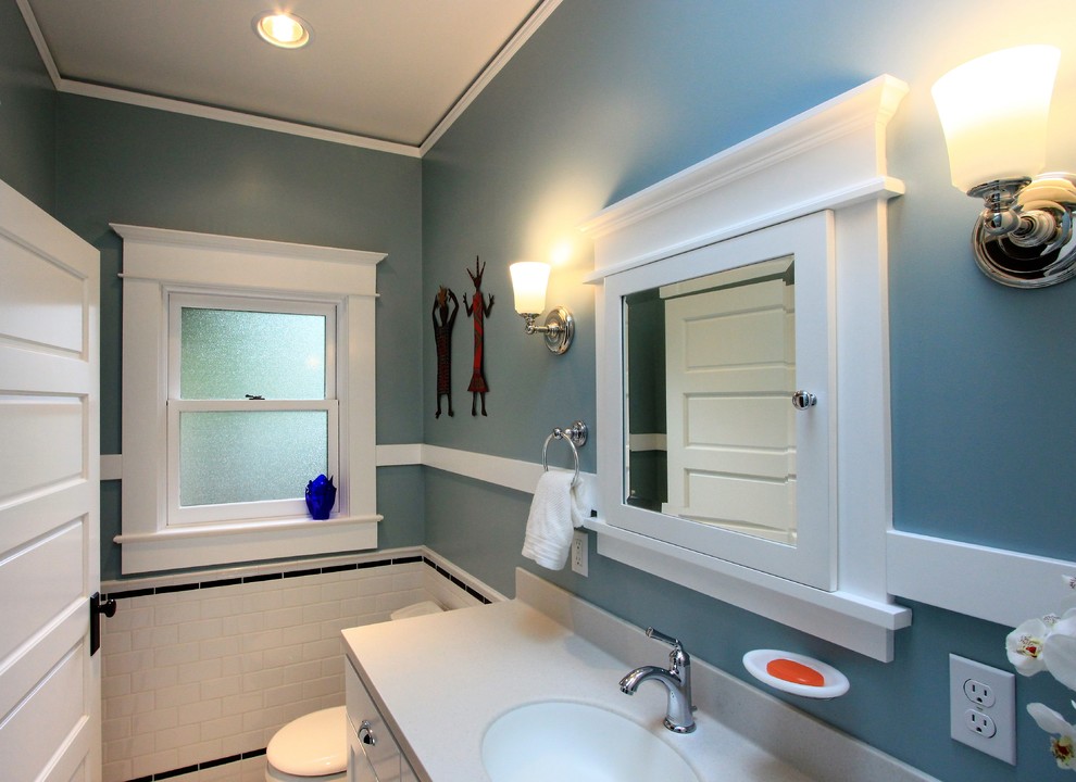 Bild på ett litet amerikanskt en-suite badrum, med skåp i shakerstil, vita skåp, en dusch i en alkov, en toalettstol med separat cisternkåpa, vit kakel, porslinskakel, blå väggar, klinkergolv i porslin, ett integrerad handfat, bänkskiva i akrylsten, vitt golv och dusch med gångjärnsdörr