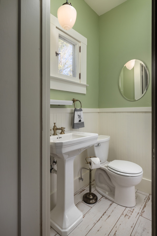 Modelo de cuarto de baño único campestre de tamaño medio con sanitario de dos piezas, lavabo con pedestal, suelo blanco, boiserie y paredes verdes