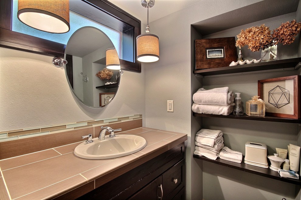 Foto di una stanza da bagno american style di medie dimensioni con ante in legno bruno, pareti grigie, lavabo da incasso e top piastrellato