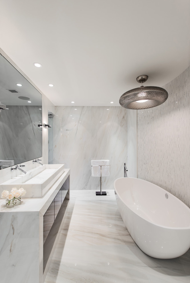 Exempel på ett modernt badrum, med ett avlångt handfat, släta luckor, ett fristående badkar och vit kakel