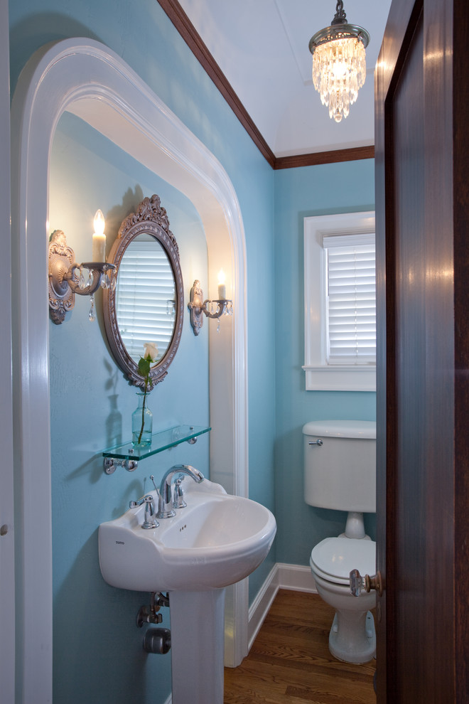 Foto på ett eklektiskt badrum med dusch, med en toalettstol med separat cisternkåpa, blå väggar, mellanmörkt trägolv och ett piedestal handfat
