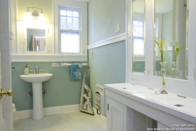 Medelhavsstil inredning av ett litet en-suite badrum, med ett piedestal handfat, luckor med upphöjd panel, vita skåp, träbänkskiva, ett platsbyggt badkar, en dusch/badkar-kombination, en toalettstol med hel cisternkåpa, vit kakel, porslinskakel, gröna väggar och klinkergolv i keramik