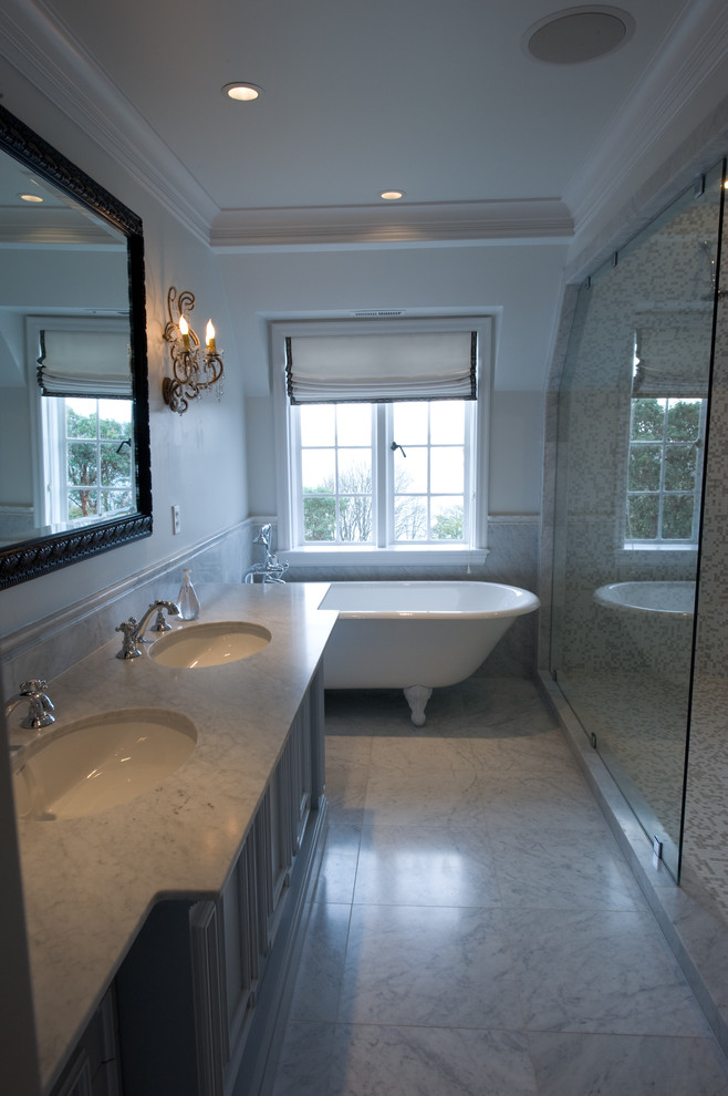 Bild på ett stort vintage en-suite badrum, med luckor med infälld panel, grå skåp, ett badkar med tassar, en dusch i en alkov, grå kakel, vit kakel, stenhäll, vita väggar, marmorgolv, ett undermonterad handfat och marmorbänkskiva