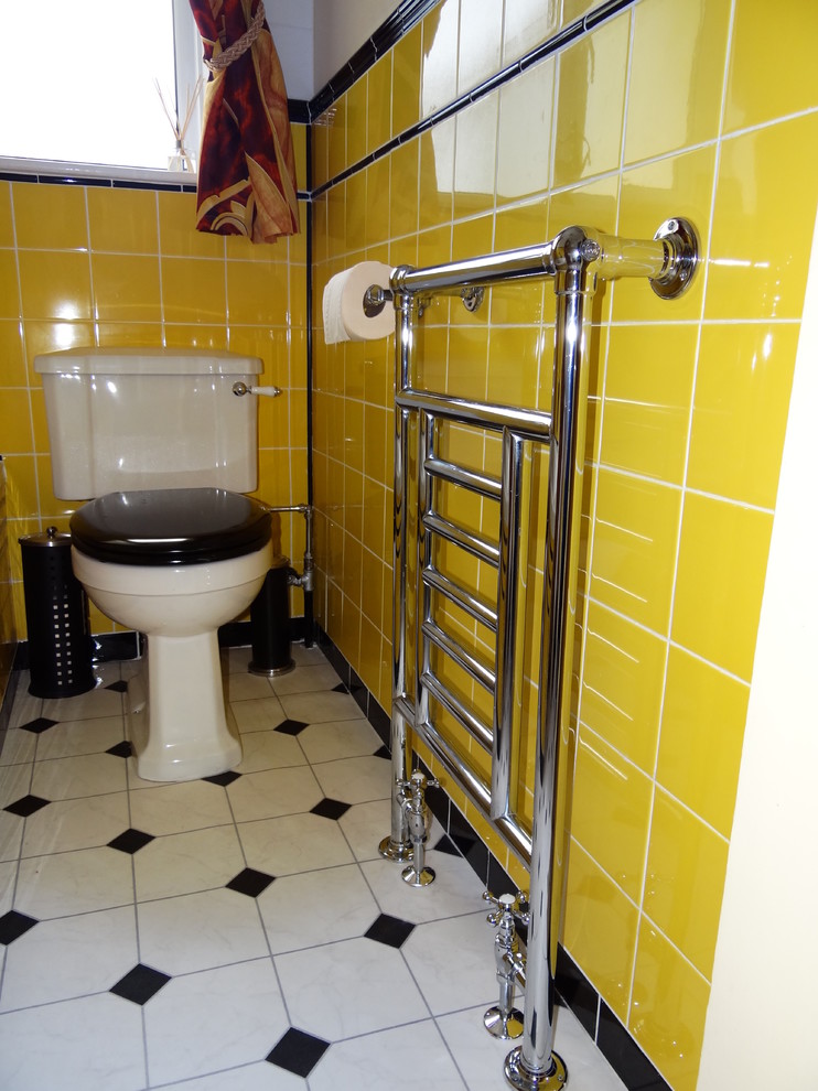 Inredning av ett 60 tals litet badrum för barn, med ett platsbyggt badkar, en dusch/badkar-kombination, en toalettstol med hel cisternkåpa, gul kakel, keramikplattor, vinylgolv och ett piedestal handfat