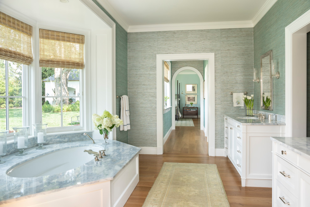 Foto på ett vintage grå en-suite badrum, med luckor med infälld panel, vita skåp, ett undermonterat badkar, grå väggar, mellanmörkt trägolv, ett undermonterad handfat och brunt golv