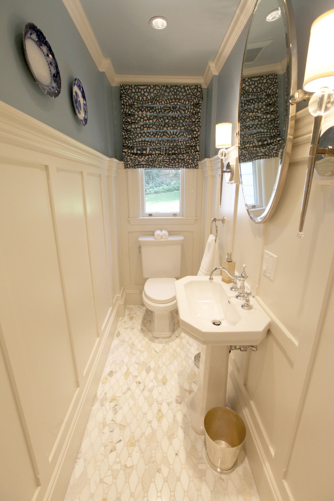 Imagen de cuarto de baño único clásico pequeño con lavabo con pedestal, sanitario de dos piezas, paredes azules, suelo de mármol, aseo y ducha, suelo blanco, puertas de armario amarillas, encimeras blancas, ventanas y panelado