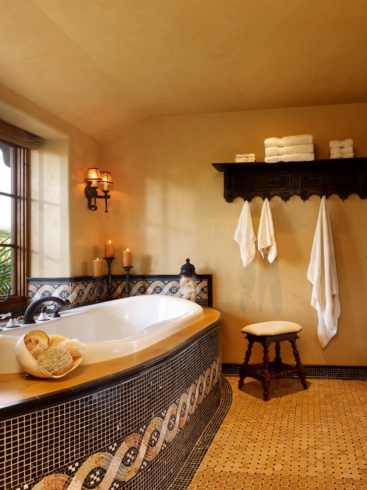 Large traditional ensuite bathroom in Other with limestone worktops, a built-in bath, multi-coloured tiles, porcelain tiles, yellow walls and porcelain flooring.