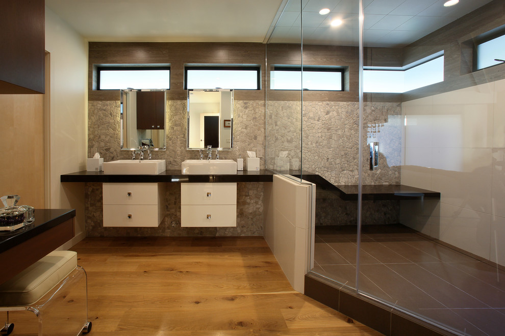 Источник вдохновения для домашнего уюта: большая главная ванная комната в стиле модернизм с фасадами островного типа, белыми фасадами, угловым душем, разноцветной плиткой, галечной плиткой, белыми стенами, светлым паркетным полом, настольной раковиной, столешницей из искусственного кварца, коричневым полом и душем с распашными дверями