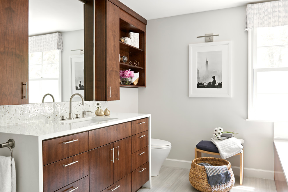 Imagen de cuarto de baño principal contemporáneo con armarios con paneles lisos, puertas de armario de madera en tonos medios, paredes grises, lavabo bajoencimera, suelo gris y encimeras blancas