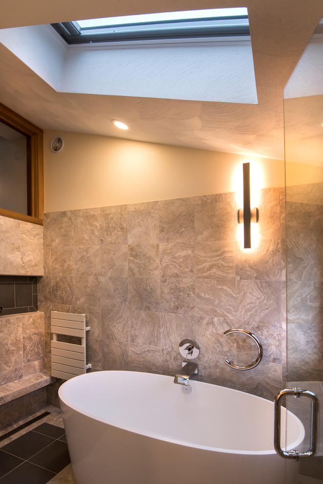 This is an example of a large contemporary ensuite wet room bathroom in Boston with flat-panel cabinets, dark wood cabinets, a freestanding bath, a one-piece toilet, grey tiles, stone tiles, beige walls, grey floors, a hinged door and white worktops.