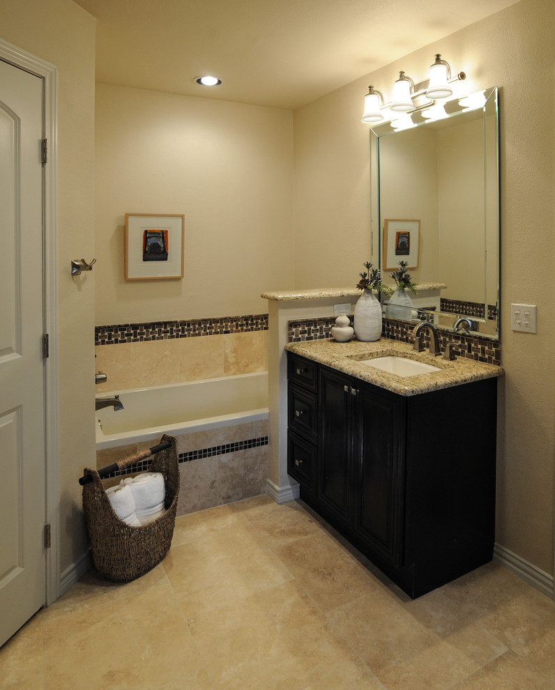 Exemple d'une salle de bain principale chic en bois foncé avec un lavabo encastré, un placard avec porte à panneau surélevé, un plan de toilette en granite, une baignoire en alcôve, un mur beige, un sol en travertin, un carrelage beige, du carrelage en travertin, un plan de toilette beige, meuble simple vasque et un sol beige.