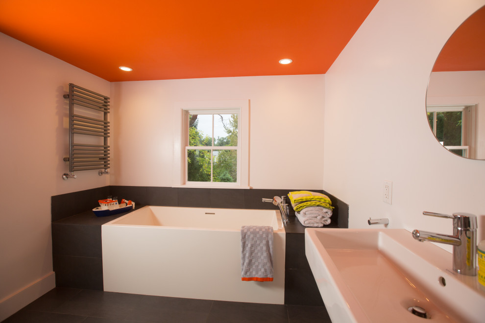 Inspiration pour une salle de bain design de taille moyenne pour enfant avec une baignoire en alcôve, un mur blanc, un plan vasque et un sol noir.
