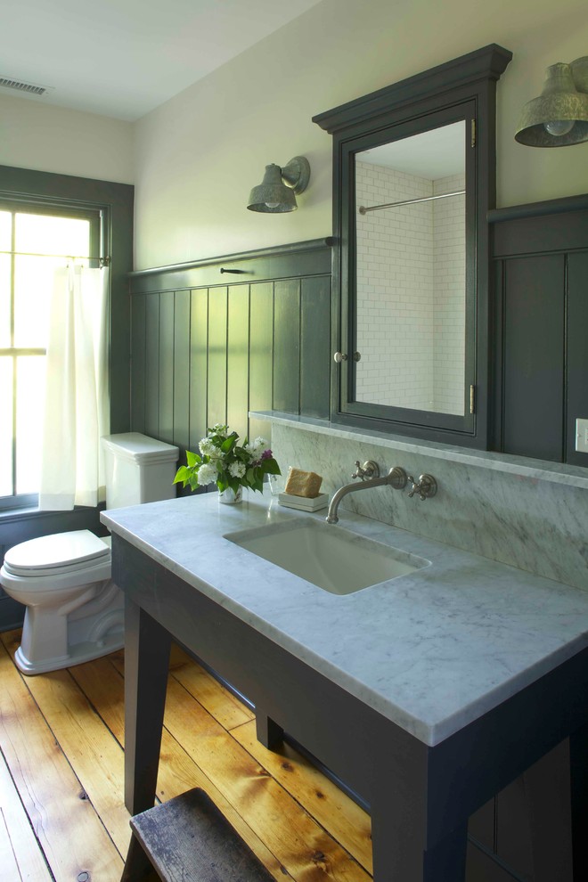 Diseño de cuarto de baño de estilo de casa de campo con encimera de mármol, lavabo bajoencimera, sanitario de dos piezas, paredes grises y suelo de madera en tonos medios