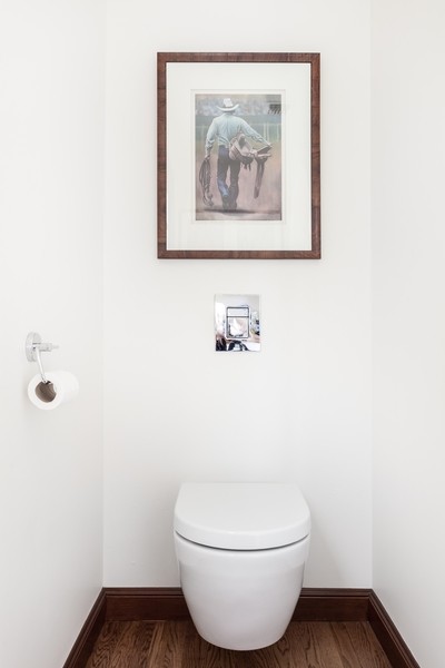 Cette image montre un grand WC suspendu méditerranéen en bois foncé avec un placard en trompe-l'oeil, un carrelage blanc, des carreaux de céramique, un mur blanc, un sol en bois brun, un lavabo intégré et un plan de toilette en bois.