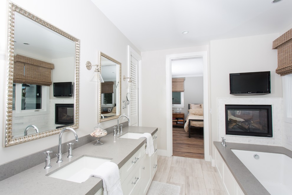 На фото: главная ванная комната в морском стиле с врезной раковиной, фасадами с утопленной филенкой, белыми фасадами, полновстраиваемой ванной, серыми стенами, полом из винила и серой столешницей с