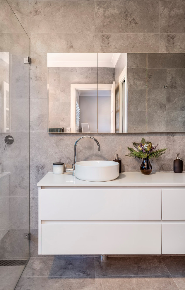 Diseño de cuarto de baño flotante actual con armarios con paneles lisos, puertas de armario blancas, baldosas y/o azulejos grises, lavabo sobreencimera, suelo gris y encimeras blancas