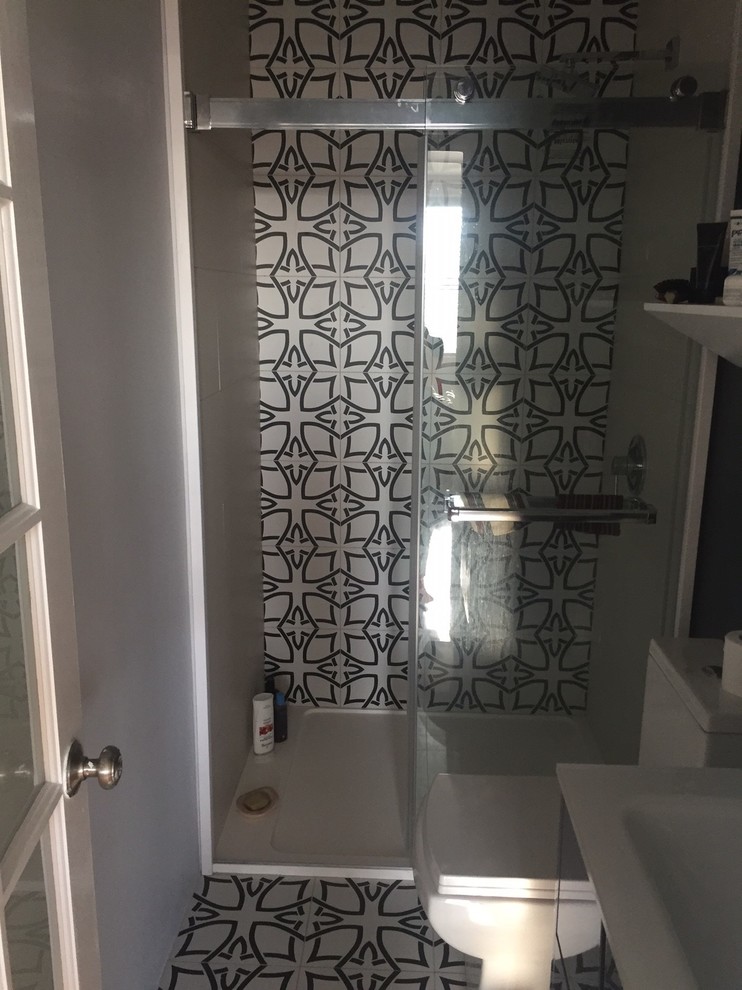 This is an example of a small shower room bathroom in New York with glass-front cabinets, black cabinets, an alcove shower, a one-piece toilet, multi-coloured tiles, cement tiles, multi-coloured walls, cement flooring, an integrated sink, multi-coloured floors and a sliding door.