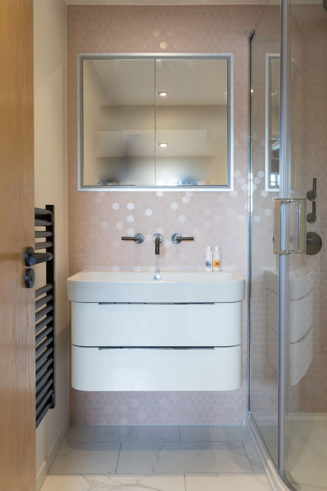 Inredning av ett modernt litet en-suite badrum, med släta luckor, vita skåp, en hörndusch, en vägghängd toalettstol, rosa kakel, keramikplattor, vita väggar, klinkergolv i keramik, ett nedsänkt handfat, grått golv och dusch med skjutdörr