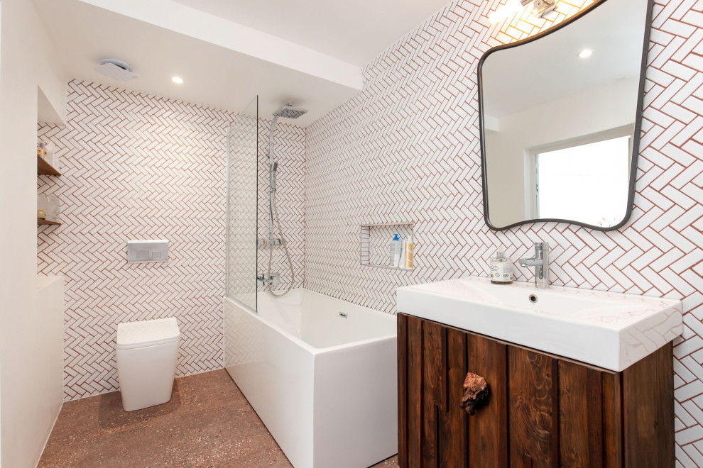 Пример оригинального дизайна: маленькая детская ванная комната в стиле модернизм с коричневыми фасадами, отдельно стоящей ванной, душем над ванной, инсталляцией, белой плиткой, керамической плиткой, белыми стенами, полом из терраццо, подвесной раковиной, столешницей из искусственного камня, красным полом, душем с распашными дверями, белой столешницей, тумбой под одну раковину, встроенной тумбой, многоуровневым потолком и кирпичными стенами для на участке и в саду