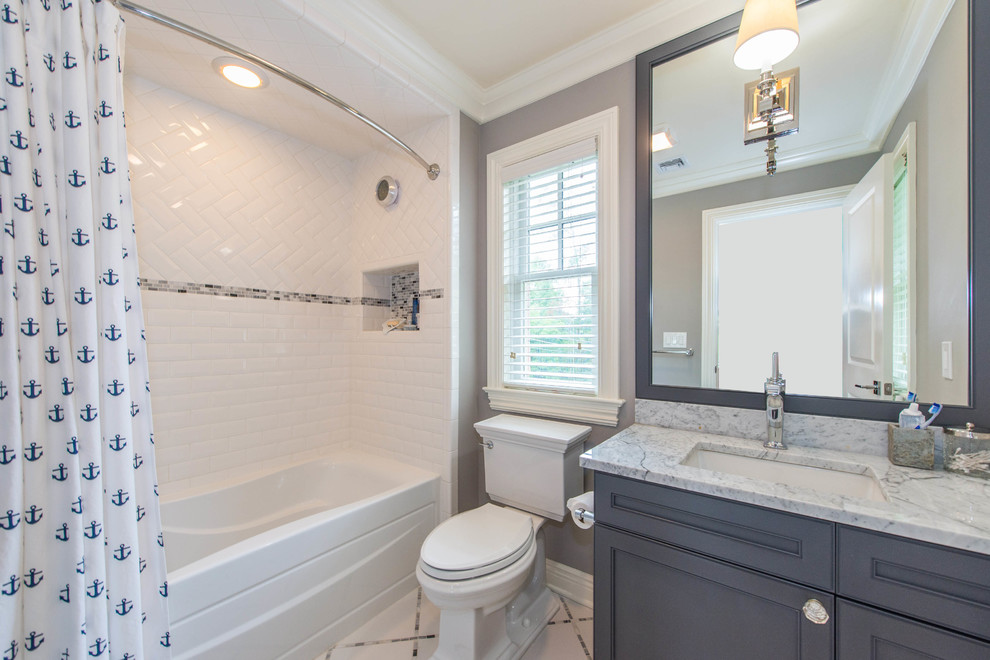 Photo of a medium sized traditional bathroom in New York with grey walls, white floors, beaded cabinets, white cabinets, an alcove bath, a shower/bath combination, a one-piece toilet, white tiles, metro tiles, a submerged sink, marble worktops and a shower curtain.