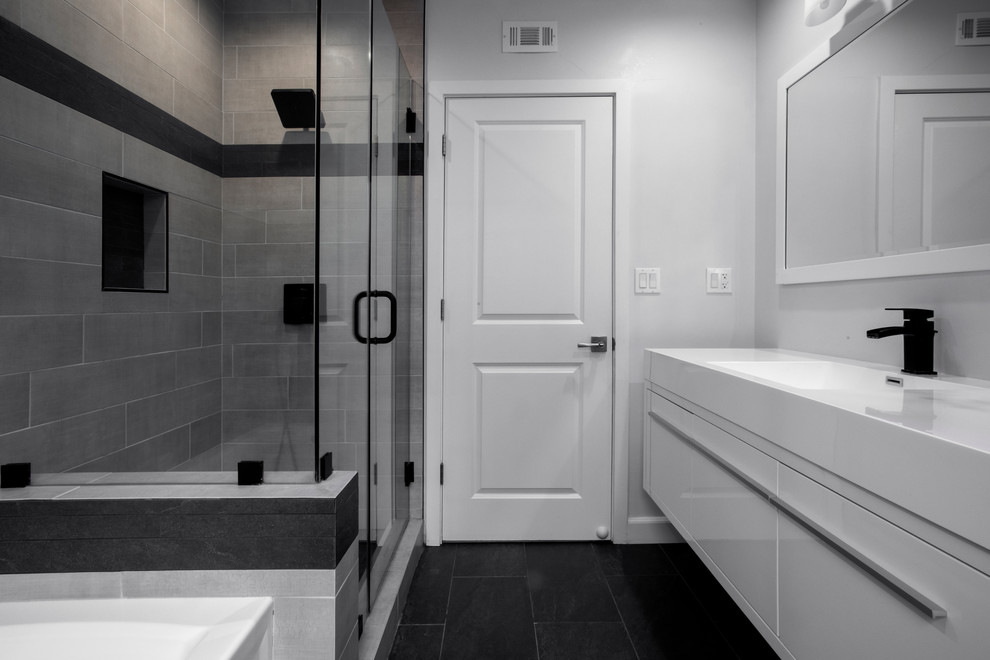 Inspiration for a medium sized modern family bathroom in Los Angeles with flat-panel cabinets, white cabinets, an alcove bath, a walk-in shower, a one-piece toilet, grey tiles, porcelain tiles, white walls, slate flooring, an integrated sink, solid surface worktops, black floors, a hinged door and white worktops.
