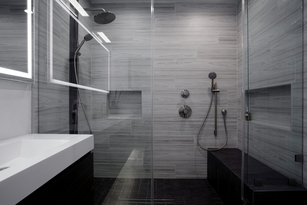 Стильный дизайн: большая главная ванная комната в стиле модернизм с плоскими фасадами, темными деревянными фасадами, двойным душем, унитазом-моноблоком, серой плиткой, керамогранитной плиткой, белыми стенами, светлым паркетным полом, монолитной раковиной, столешницей из искусственного камня, бежевым полом, душем с распашными дверями и белой столешницей - последний тренд