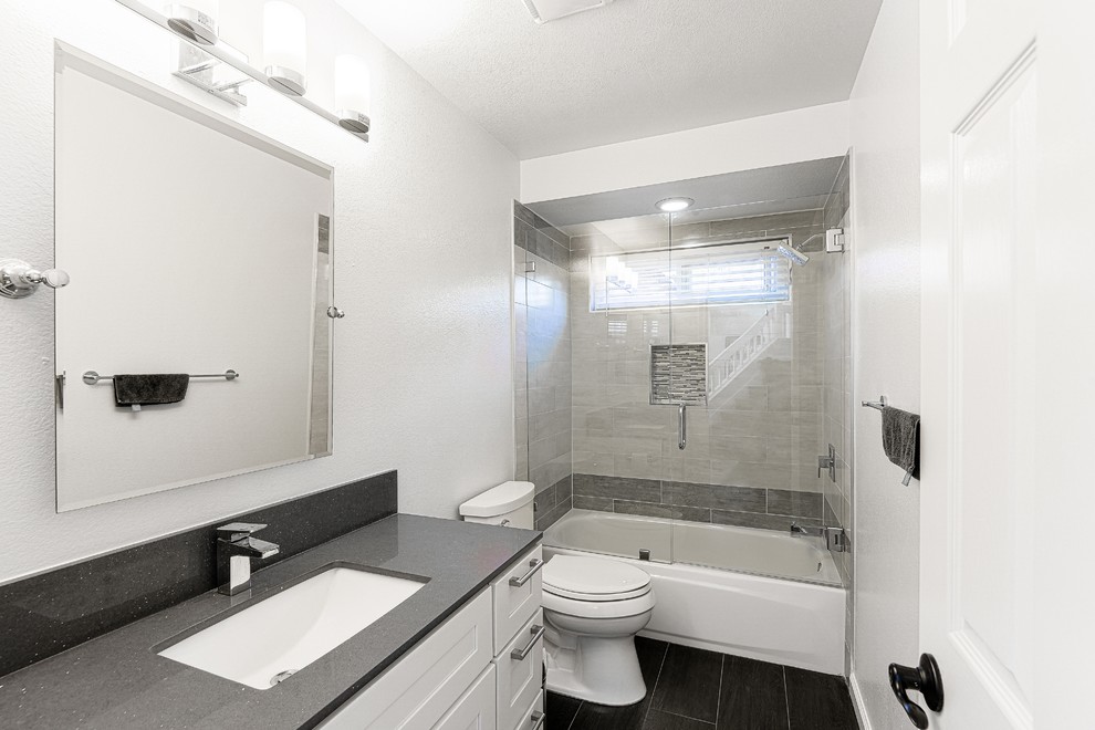 Idéer för ett mellanstort modernt grå badrum med dusch, med skåp i shakerstil, vita skåp, ett badkar i en alkov, en dusch/badkar-kombination, en toalettstol med hel cisternkåpa, vita väggar, vinylgolv, ett undermonterad handfat, granitbänkskiva, svart golv och dusch med gångjärnsdörr