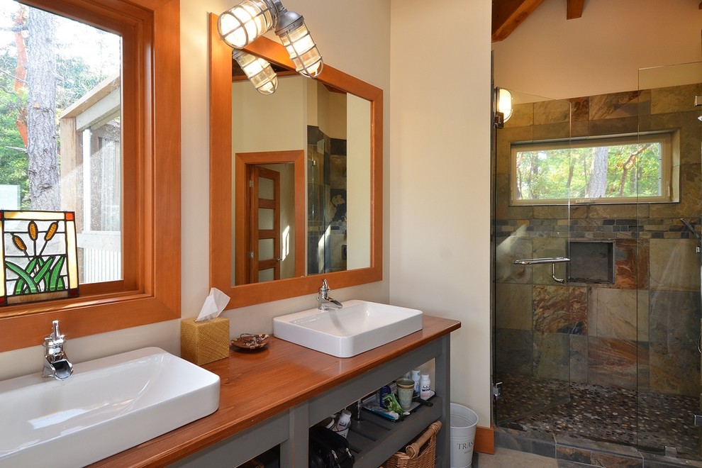 Inredning av ett klassiskt mellanstort en-suite badrum, med ett fristående handfat, öppna hyllor, grå skåp, träbänkskiva, en kantlös dusch, flerfärgad kakel, porslinskakel och beige väggar