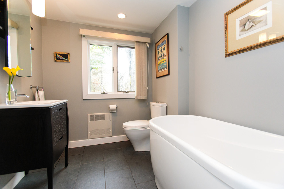 Inspiration för stora moderna badrum med dusch, med ett fristående badkar, en toalettstol med separat cisternkåpa, grå kakel, grå väggar, klinkergolv i keramik, ett konsol handfat, bänkskiva i akrylsten och svart golv
