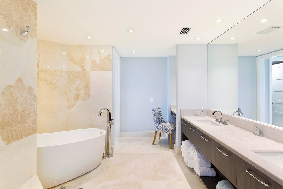 Пример оригинального дизайна: главная ванная комната среднего размера в стиле неоклассика (современная классика) с плоскими фасадами, коричневыми фасадами, отдельно стоящей ванной, бежевой плиткой, синими стенами, врезной раковиной, бежевым полом, бежевой столешницей, унитазом-моноблоком, плиткой из известняка, полом из керамогранита и мраморной столешницей