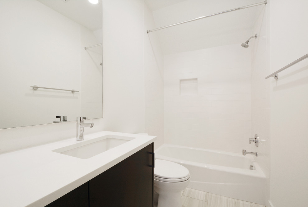 Inspiration for a mid-sized modern kids' white tile and subway tile ceramic tile tub/shower combo remodel in Austin with an undermount sink, flat-panel cabinets, black cabinets, quartz countertops, a two-piece toilet and white walls