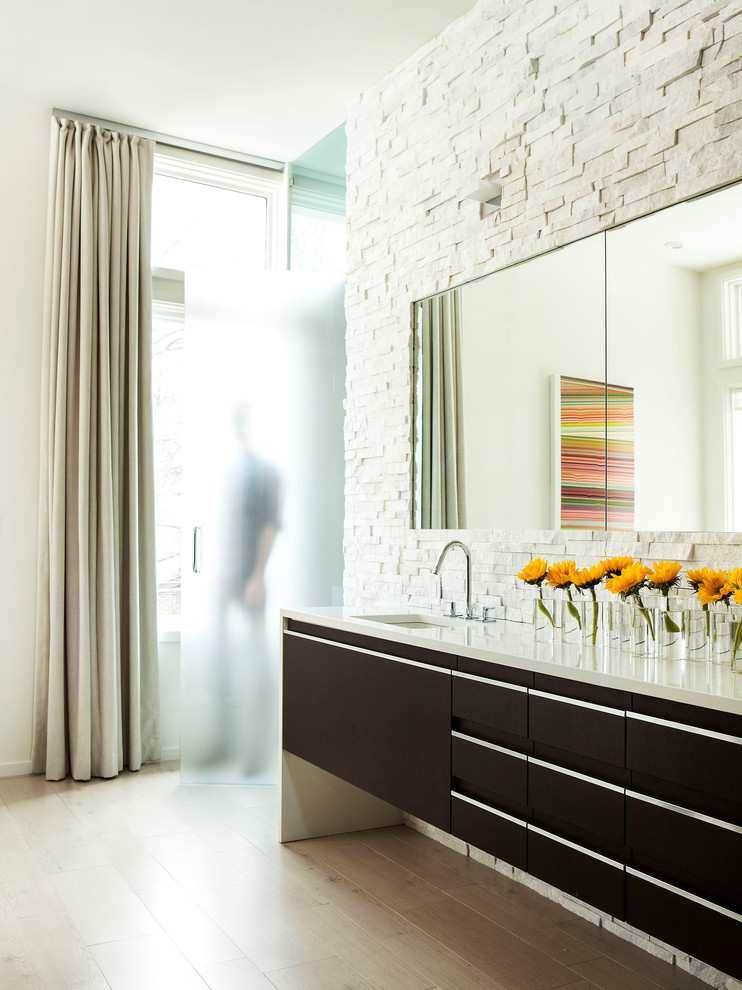 Пример оригинального дизайна: ванная комната в современном стиле с врезной раковиной, плоскими фасадами, темными деревянными фасадами, столешницей из искусственного камня, отдельно стоящей ванной, белой плиткой и керамогранитной плиткой