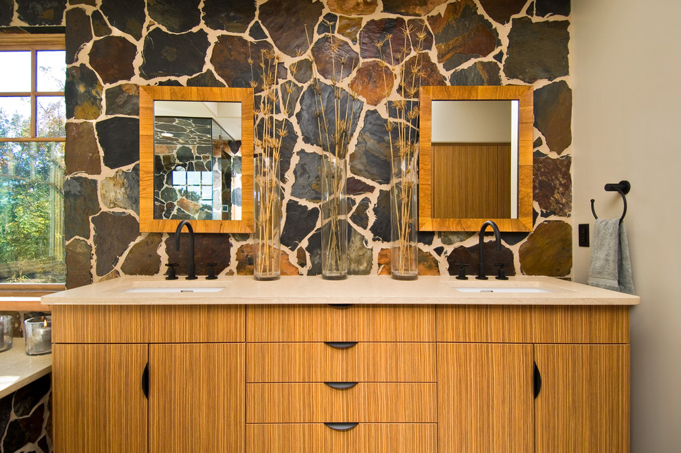 Inspiration pour une salle de bain chalet en bois brun avec un lavabo encastré, un placard à porte plane et un mur en pierre.