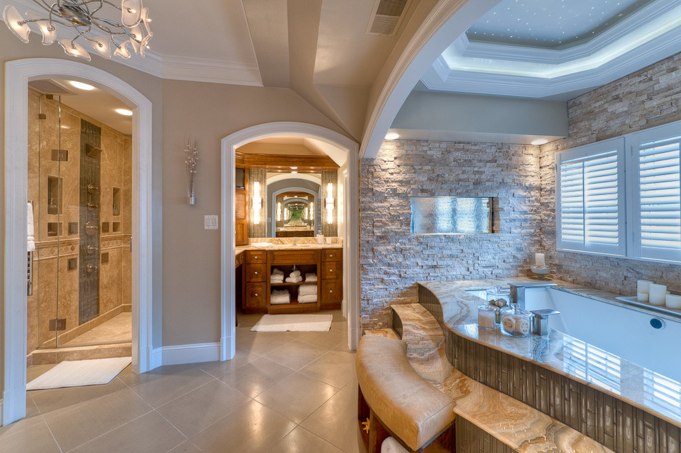 Cette image montre une grande salle de bain design en bois brun avec un lavabo encastré, un placard à porte shaker, un plan de toilette en granite, une baignoire encastrée, WC séparés, un carrelage beige, un carrelage de pierre, un mur beige et un sol en travertin.