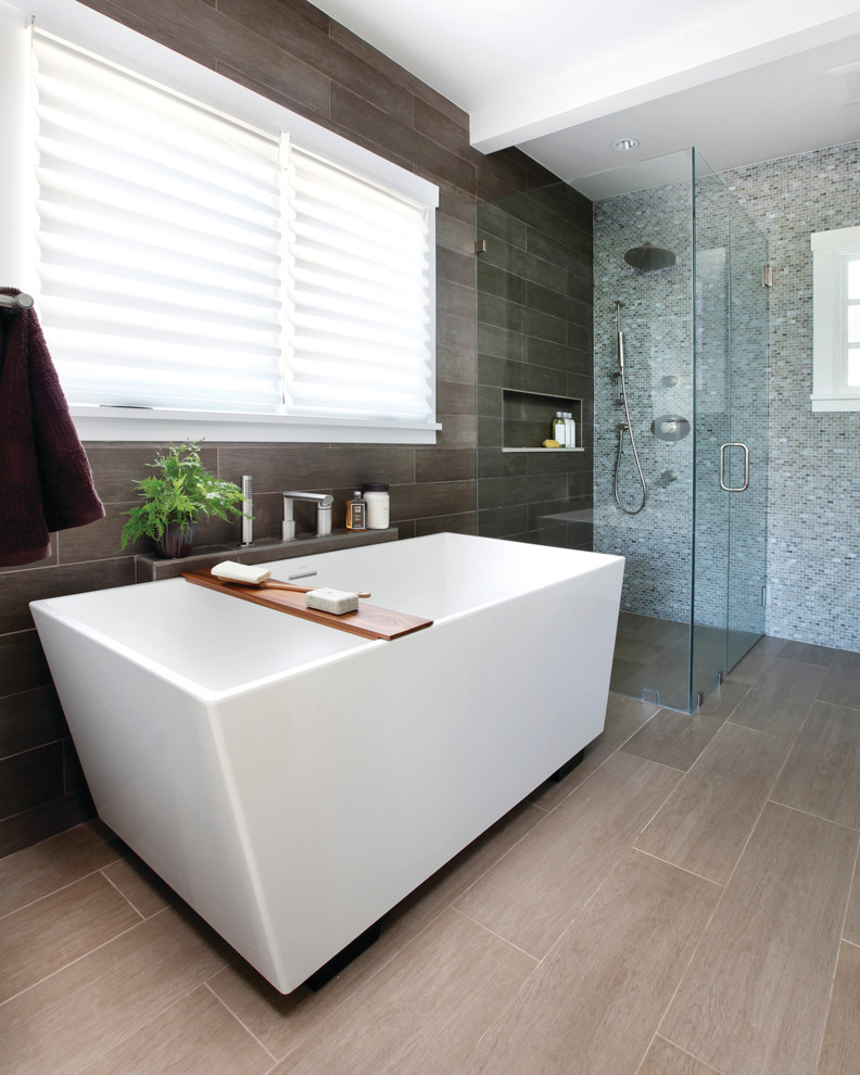 Photo of a contemporary bathroom in New York with a freestanding bath, a built-in shower and grey tiles.