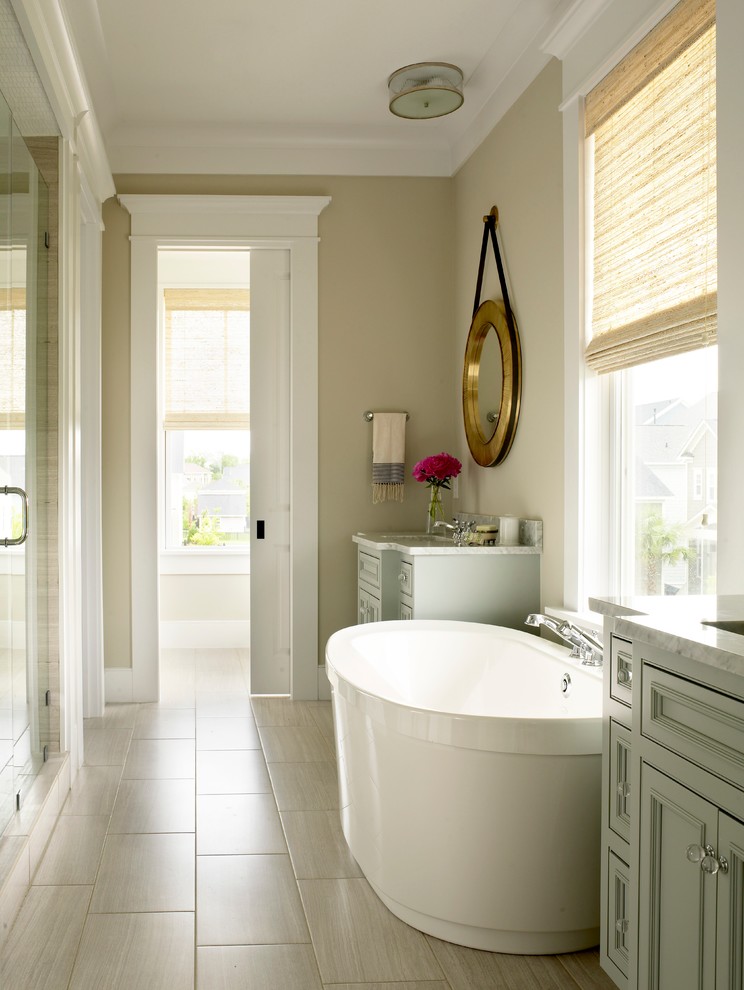 Modelo de cuarto de baño tradicional renovado con lavabo bajoencimera, armarios con paneles empotrados, encimera de mármol, bañera exenta, ducha empotrada, baldosas y/o azulejos grises y paredes beige