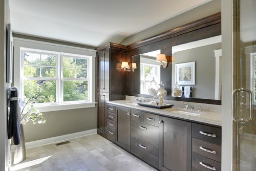 Double-sink bathroom vanity with dark wood shaker bathroom cabinets, quartz countertop, wide mirror, chrome pulls, and wall sconces.