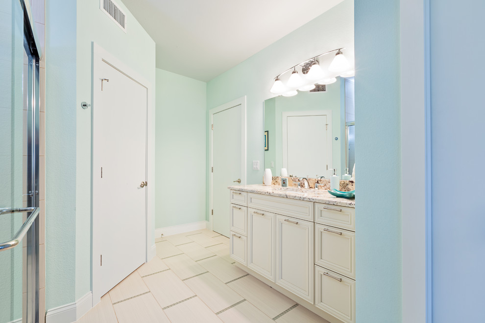 Inspiration for a medium sized coastal bathroom in Tampa with recessed-panel cabinets, white cabinets, an alcove shower, blue walls, a submerged sink and granite worktops.