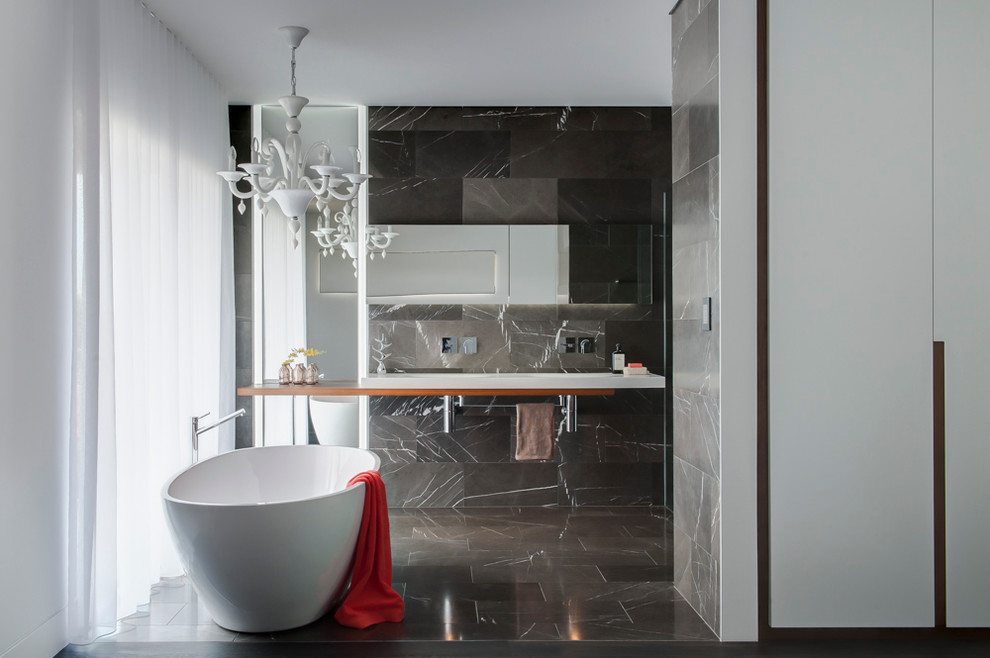 На фото: главная ванная комната среднего размера в современном стиле с столешницей из дерева, отдельно стоящей ванной, открытым душем, черно-белой плиткой, плиткой из листового камня, серыми стенами, мраморным полом и раковиной с несколькими смесителями