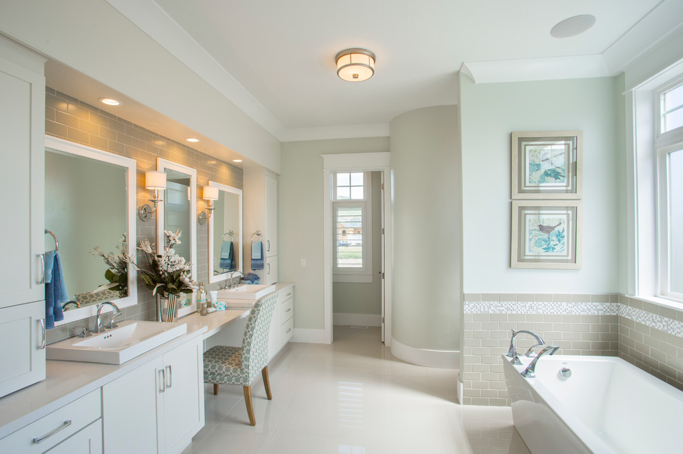 Cette image montre une salle de bain principale traditionnelle de taille moyenne avec un placard à porte shaker, des portes de placard blanches, une baignoire indépendante, un carrelage gris, des carreaux de céramique, un mur vert, un sol en carrelage de porcelaine, un lavabo posé, un plan de toilette en marbre et un sol beige.