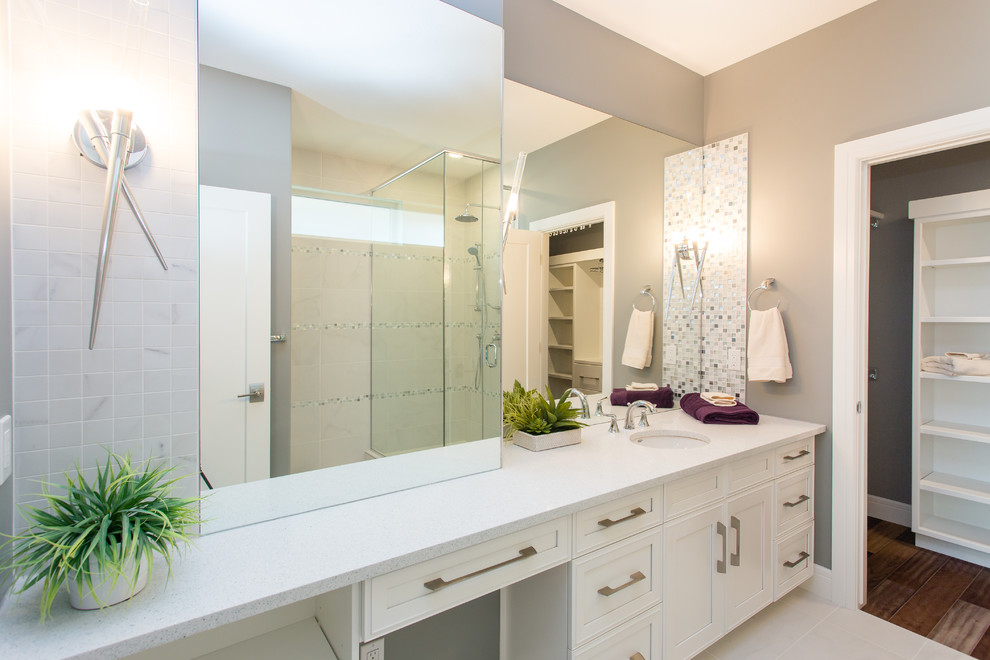 Exemple d'une salle de bain principale tendance de taille moyenne avec un lavabo encastré, un placard avec porte à panneau encastré, des portes de placard blanches, un plan de toilette en quartz modifié, une douche d'angle, un carrelage blanc et un mur gris.