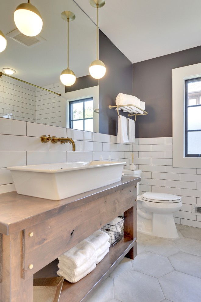 Exemple d'une petite salle d'eau tendance en bois brun avec une grande vasque, un placard en trompe-l'oeil, un plan de toilette en bois, un combiné douche/baignoire, WC séparés, un carrelage gris, des carreaux de porcelaine, un mur bleu et un sol en carrelage de porcelaine.