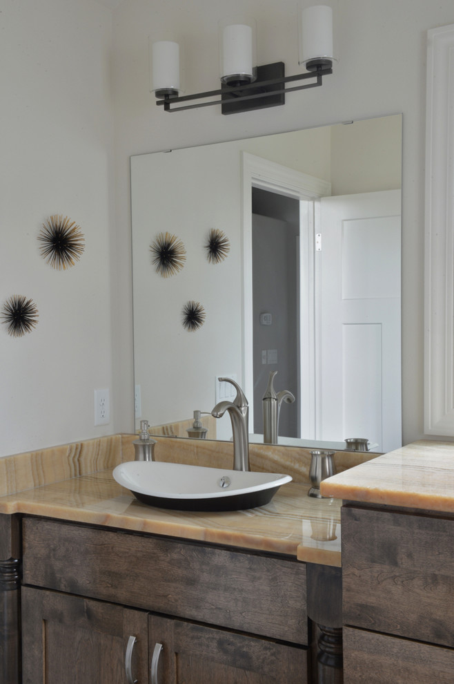 Idée de décoration pour une salle de bain principale minimaliste en bois brun de taille moyenne avec une vasque, un placard à porte plane, un plan de toilette en onyx, une douche à l'italienne, WC à poser, un carrelage gris, des carreaux de porcelaine, un mur gris et un sol en carrelage de porcelaine.