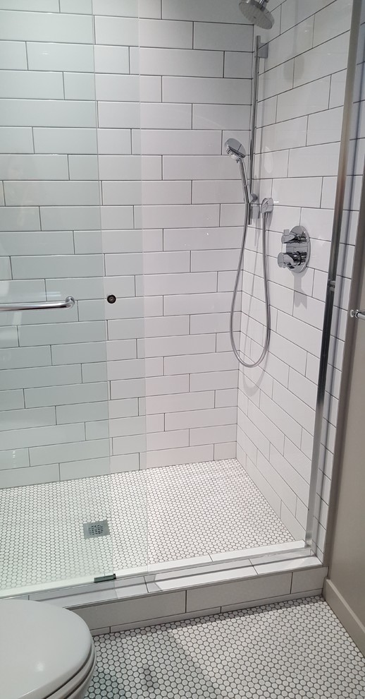 Inredning av ett klassiskt mellanstort en-suite badrum, med vita skåp, vit kakel, en dusch i en alkov, en toalettstol med separat cisternkåpa, tunnelbanekakel, vita väggar, klinkergolv i porslin och dusch med skjutdörr