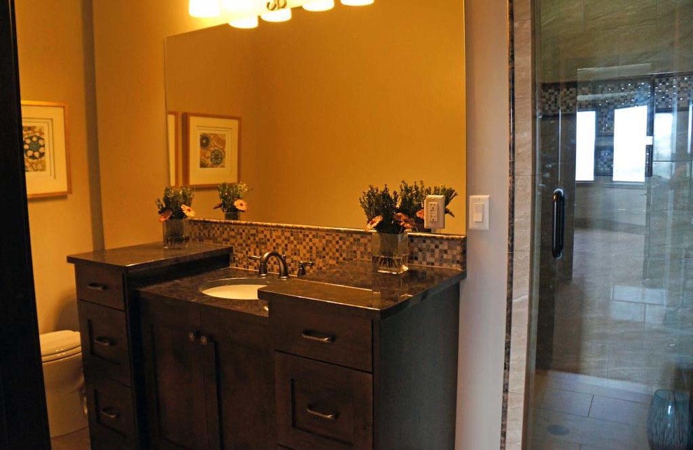 Bild på ett stort rustikt badrum med dusch, med luckor med upphöjd panel, skåp i mörkt trä, en dusch i en alkov, en toalettstol med hel cisternkåpa, beige kakel, glaskakel, vita väggar, klinkergolv i keramik, ett nedsänkt handfat och granitbänkskiva