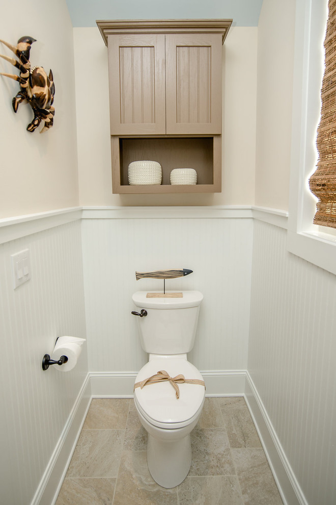 Cette photo montre un petit WC et toilettes craftsman avec un placard avec porte à panneau encastré, des portes de placard marrons, WC séparés, un carrelage beige, un mur blanc, un sol en bois brun et un lavabo encastré.