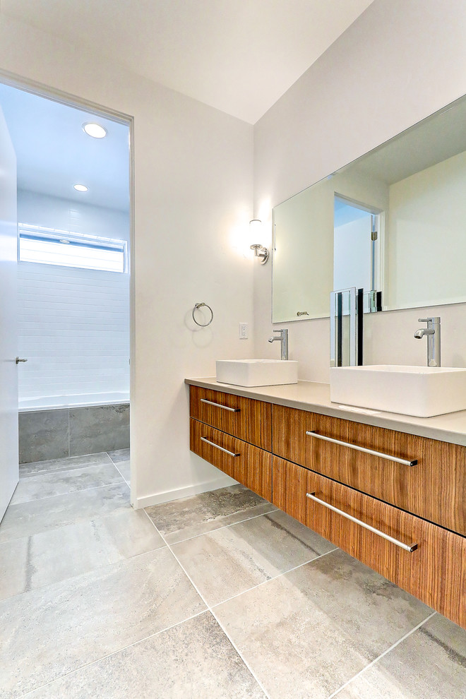 Mid-sized trendy kids' multicolored tile and porcelain tile porcelain tile bathroom photo in Boise with flat-panel cabinets, medium tone wood cabinets, a wall-mount toilet, white walls, a vessel sink and quartz countertops